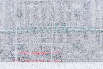 city red bus during heavy snowfall with old building in a background