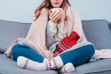 Woman freezes in wintertime. Young girl wearing warm woolen socks and wrapped into two blankets,...