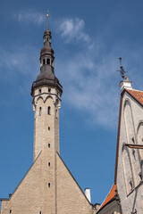 Fototapeta na wymiar Estonia, Tallinn - July 21, 2022: Closeup, Town Hall tower against blue sky seen from Raekoja street. Facades on sides