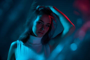 Portrait of young beautiful woman posing isolated over blue studio background in neon light. Lifestyle