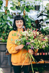 Woman arranges bouquet from flowers in florist shop