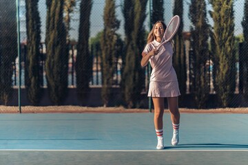 Young female in pink athleisure playing tennis with a pink racket on a court