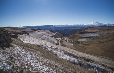 View of the mountain range and hills with snow in November in sunny weather, hills in the mountains with snow and Mount Elbrus