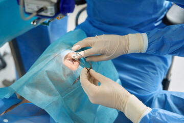 Doctor holding eyelid expander during the surgery