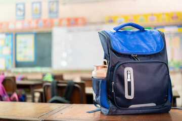 Front of stylish school bag backpack supplies on a table desk at the green chalkboard, Back to...