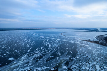 Obraz premium Breakwater leading into Baltic sea at winter. Sea covered in fog and ice blocks.