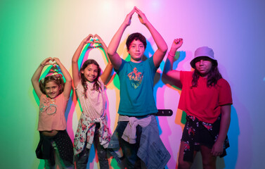 A group of pre-teen boys stand with coloured strobe lights, making shadows on the wall and posing...