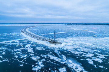 aerial view of a lonely lighthouse in the frozen sea. Frozen blue ice in cracks