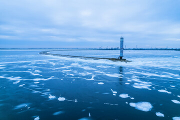 Fototapeta premium aerial view of a lonely lighthouse in the frozen sea. Frozen blue ice in cracks