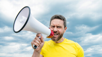 man in yellow shirt warning in loudspeaker on sky background