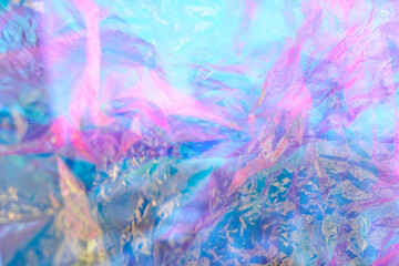 Transparent holographic wrinkled polyethylene background. Holographic colorful plastic film in blue, purple and pink tones with copy space. High quality photo