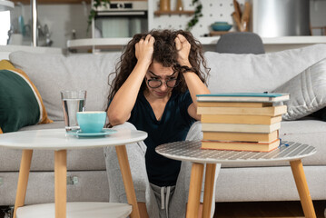 Young sick nervous schoolgirl or student is trying to study remotely from home for exam but can't because of loud noise from apartment above due to renovation work or birthday party. Poor insulation