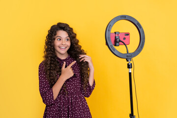 smiling child with long curly hair making video for blog
