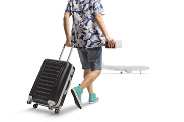Rear view shot of a male passenger pulling a suitcase and walking towards a plane