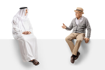 Senior gentleman sitting on a panel and talking to a muslim man in ethnic clothes