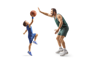 Full length profile shot of an adult basketball player playing basketball with a child