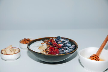 Yoghurts in green plate with blueberries, raspberries, chia seeds and granola with a wooden board. The concept of healthy eating. Front view
