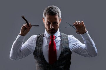 handsome unshaven man hairdresser hold blade and scissors isolated on grey background.