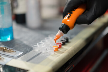The process of pouring tattoo ink into a container, tattoo studio. Tattoo artist in studio preparing
