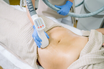 Obraz na płótnie Canvas Unrecognizable client and cosmetologist during vacuum tummy massage