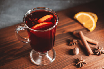 Mulled red wine in a glass and spices on wooden background