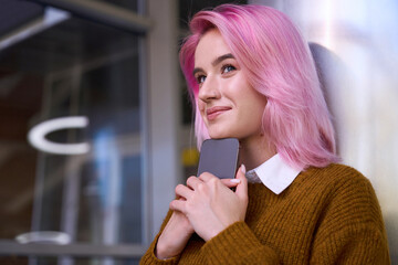 Smiling young lady with pink hair waiting for call