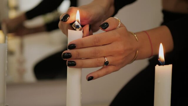 Unrecognizable woman in black dress and nails lights candles, closeup. Female hand preparing for the magic ritual