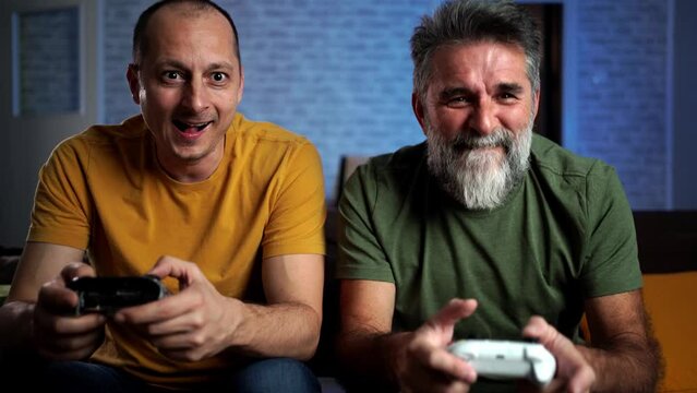 4K video footage of a Happy Friends on the Sofa Playing Video Games, Using Controllers. Competitive Friends have Fun Playing in Online Video Games at Home Together