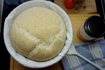 raw Sourdough bread in fermentation basket with sourdough starter in glass