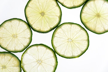 Slices of green fresh lime on a white background on the lumen. Close-up shooting.