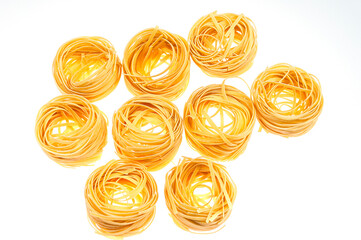 Nests of raw pasta on a white background.