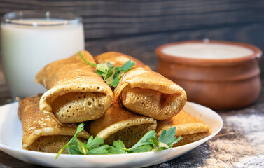 Homemade savory pancakes stuffed with meat on the background of milk and cream 