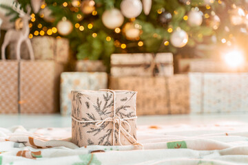 Christmas atmosphere. The gift box lies in the middle of the room next to the Christmas tree and garlands.