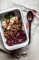 Baked chicken legs on a baking sheet with boiled buckwheat.