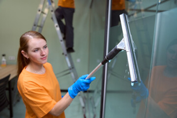 Hard-working woman cleaning a transparent surface with special mop