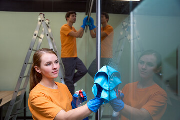 Two cleaner company employees wiping and disinfecting a glass surface