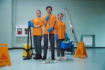 Young workers of cleaning company posing with their tools