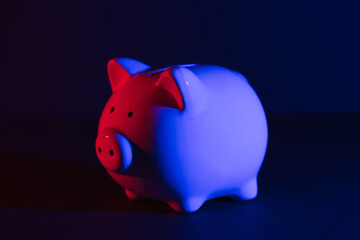 Piggy bank on a dark background with red-blue backlight. Banking concept. Bright neon lights on a black background