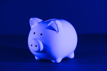 Piggy bank on a dark background with blue backlight. Banking concept. Bright neon lights
