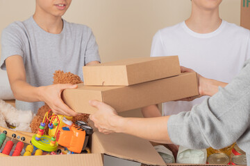 Young volunteers collect donations for charity indoors. Donation boxes with clothes, food, toys,...