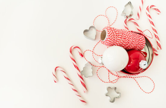 Christmas candies, along with cookie cutters, Christmas tree toys and red thread for gift wrapping, lie on a white table. Selective focus, noise. Christmas and New Year 2023-2024.