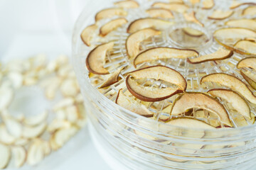 The process of homemade dried fruit or candied fruit in an electric dryer on the table. Fruits for...