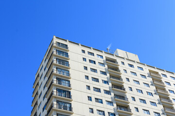 Exterior view of a typical multifamily mid and high rise residential building under blue sky. Looking up at rental apartment, college dorm, condominium, assisted-living facility building