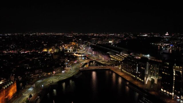 Amsterdam city center skyline by night aerial drone overhead view. Amsterdam Centraal, Ij, Oosterdok, Prins Hendrikkade, public transport, traffic at night. Bright lights urban