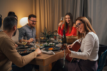 Young woman plays guitar to her friends