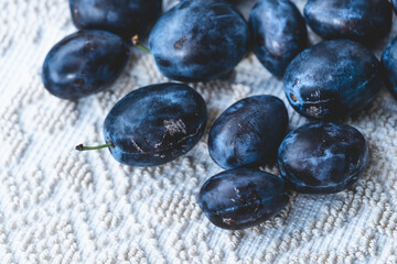 Fruit background, organic fruits. Still life food. Raw fresh blue plums on a textured table cloth. 
