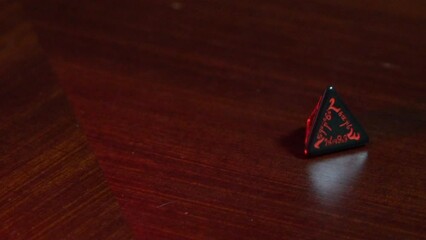 A four sided red dice being rolled in slow motion. - Powered by Adobe