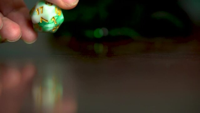 Hand picking up green dice off table.