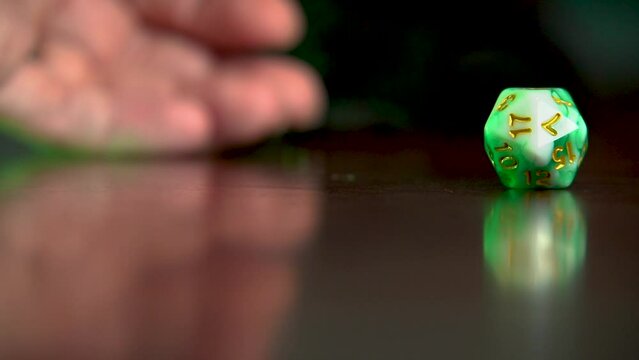 Hand rolling a 20 sided dice into view.
