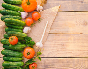 Fresh vegetables on a wooden background. Empty space for the text. Cucumbers, tomatoes, garlic, dill. Top view.
